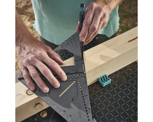 Osoba používá multifunkční úhelník k označení dřevěné desky.