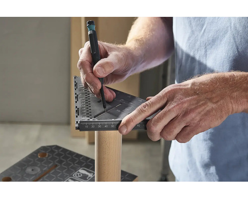 Osoba používá úhelník a tužku k označení kusu dřeva.