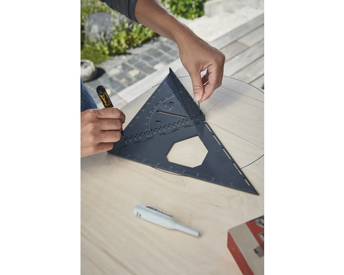 Řemeslník pracuje s tesařským úhelníkem na dřevěné desce a kreslí kruh.