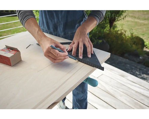 Osoba kreslí tužkou a úhelníkem na dřevo