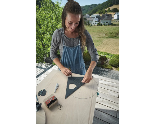 Žena kreslí kruh pomocí tesařského úhelníku na dřevěnou desku