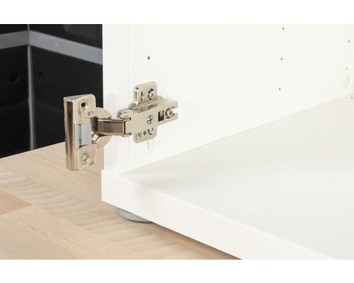 Nábytkový pant připevněný k bílé skříňce