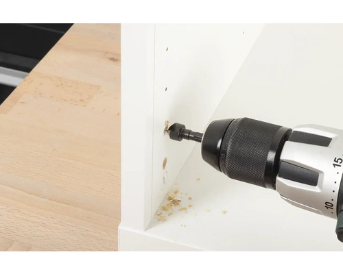 Vrtačka vrtá otvor do bílého kusu nábytku.