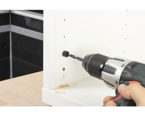 Vrtačka vrtá otvor do bílého kusu nábytku.