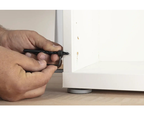 Osoba používá vrták do dřeva s hloubkovým dorazem na bílý nábytek.