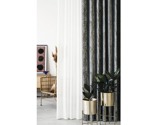 Dekorativní uspořádání pokoje se závěsy, ratanovým křeslem a pokojovými rostlinami ve zlatých květináčích