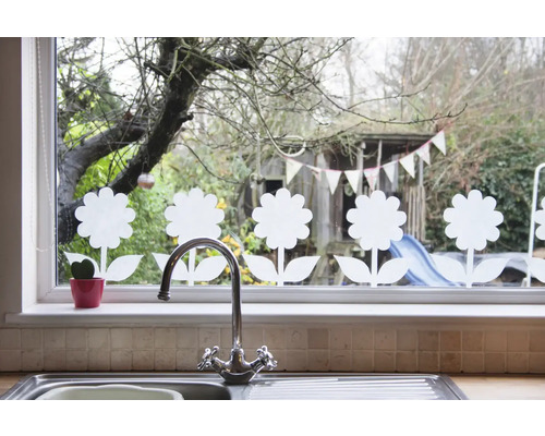 Dekorace oken s květinovými motivy, v popředí dřez a vodovodní kohoutek