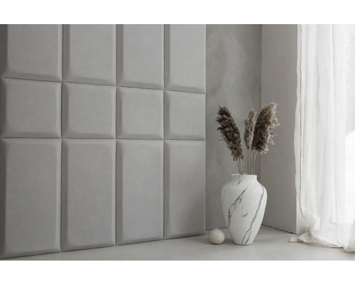 Scéna se čtvercovými nástěnnými panely, vázou a dekorativními prvky v místnosti.