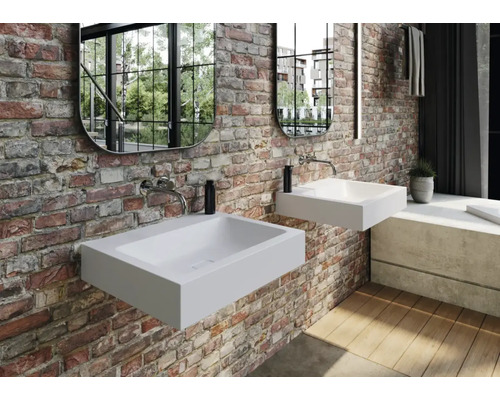 Moderní koupelna se dvěma bílými umyvadly na desku, zrcadly a zdmi z odhalených cihel.