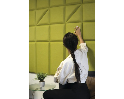 Žena se dotýká akustického panelu s geometrickým vzorem na zdi