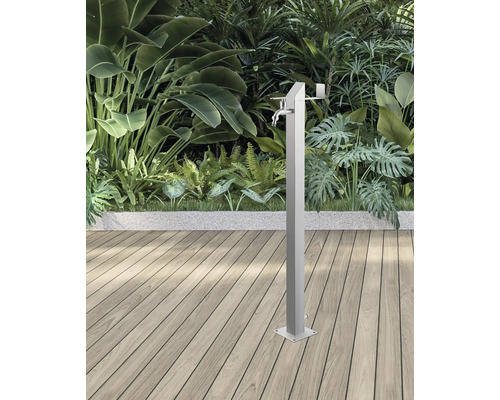 Kovová zahradní sprcha s vodovodním kohoutkem před rostlinami