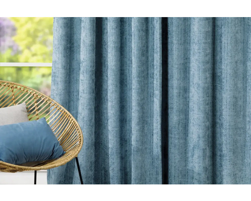 Dekorativní světle modrý závěs vedle ratanového křesla před oknem