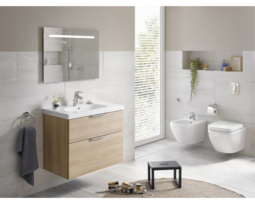 Světlá koupelna s umyvadlem, zrcadlem, toaletou a bidetem.