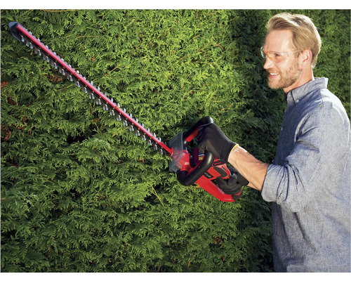 Muž stříhá živý plot pomocí akumulátorových nůžek na živý plot