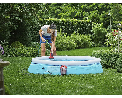 Žena používá ponorné čerpadlo k odstranění vody z bazénu na zahradě.
