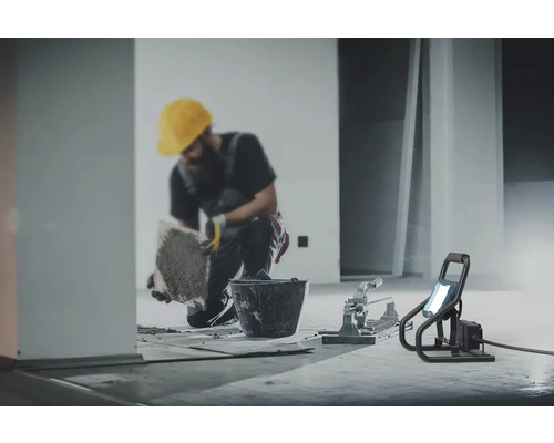 Řemeslník pokládá dlaždice s nářadím a stavebním reflektorem