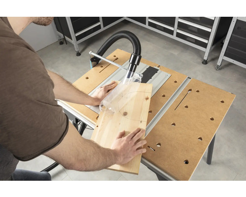 Osoba řeže kus dřeva stolní pilou v dílně.