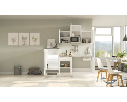 Kompaktní kuchyň s lednicí, dřezem, mikrovlnnou troubou a úložným prostorem v světlé místnosti.