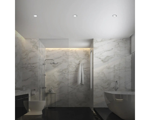 Světlá koupelna se sprchou, vanou, toaletou a mramorovými obklady.