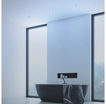 Moderní koupelna s volně stojící vanou, ručníkem a stropními bodovými svítidly.