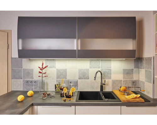 Moderní kuchyně s dřezem, baterií, pracovní deskou a závěsnými skříňkami.