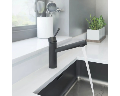 Černá kuchyňská baterie s tekoucí vodou v moderním kuchyňském designu.