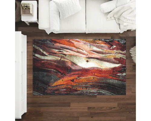 Pohled shora na obývací pokoj s pohovkou a kobercem s abstraktním vzorem na dřevěné podlaze