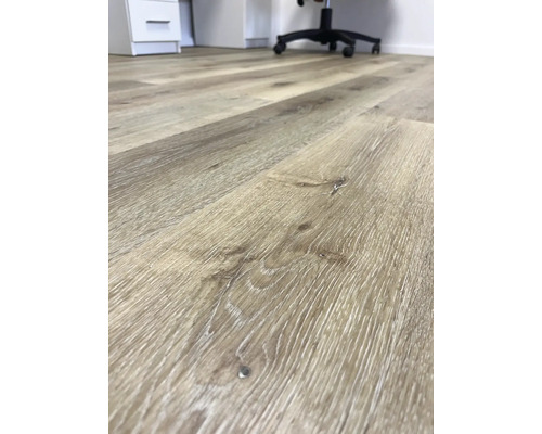 Detail světlé laminátové podlahy s dřevěným vzhledem v kanceláři.