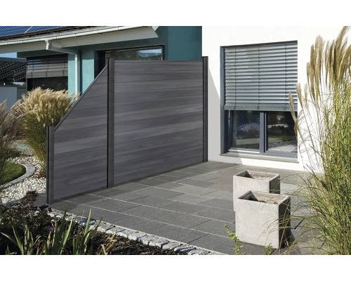 Dřevěný plot v zahradní oblasti s rostlinami a dlažebními kostkami