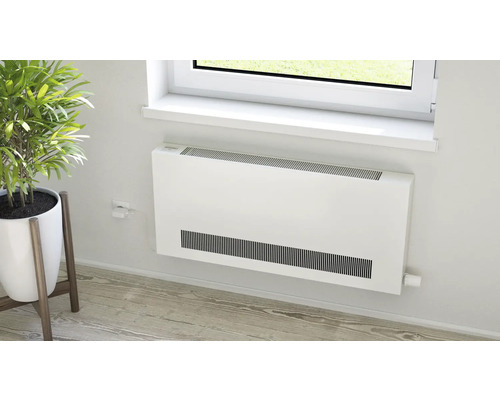 Plochý radiátor pod oknem ve světlé místnosti.