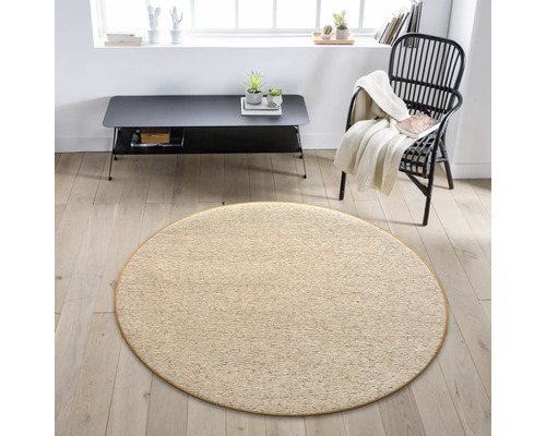Béžový kulatý koberec v obývacím pokoji s křeslem a stolem