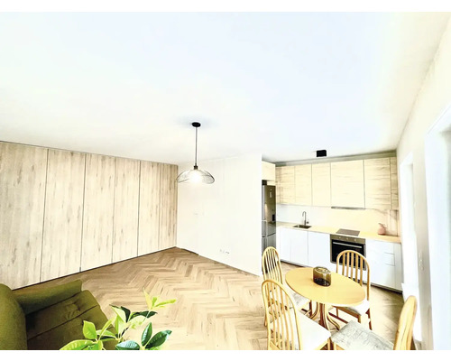 Světlý obývací pokoj s kuchyní, jídelním stolem a dřevěnou podlahou.