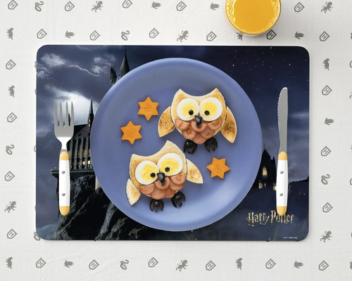 Prostřený stůl s prostíráním Harry Potter, talíř s tvarem sovy z chleba, klobásy, vejce a sýra, plus příbory a pomerančový džus