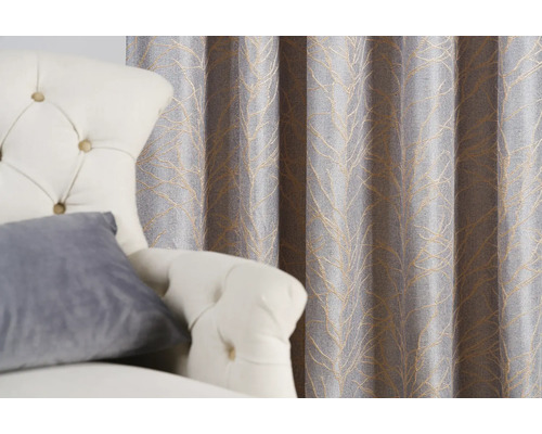 Dekorativní šedý závěs se vzorem listů vedle křesla