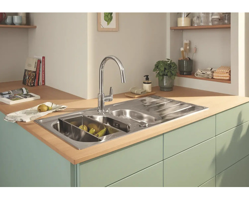 Nerezový kuchyňský dřez s odkapávačem a vodovodní baterií ve světlé kuchyni