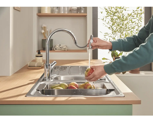 Kuchyňský dřez s vodovodní baterií a osobou myjící ovoce