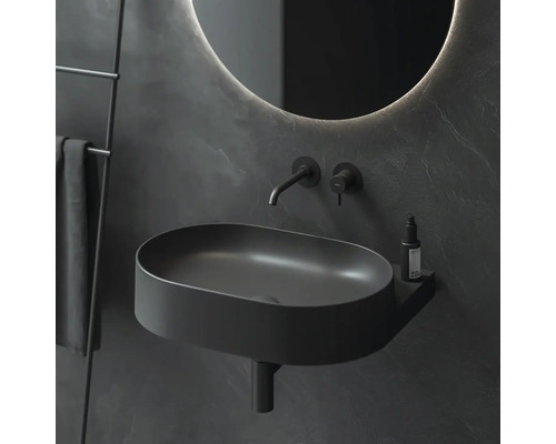 Moderní koupelna s černým umyvadlem, vodovodní baterií, kulatým zrcadlem a držákem na ručníky.