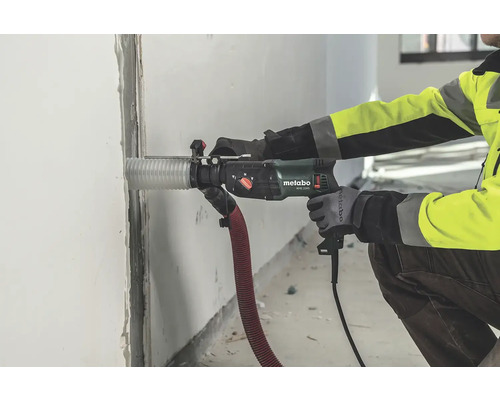 Pracovník vrtá vrtacím kladivem Metabo otvor do zdi.
