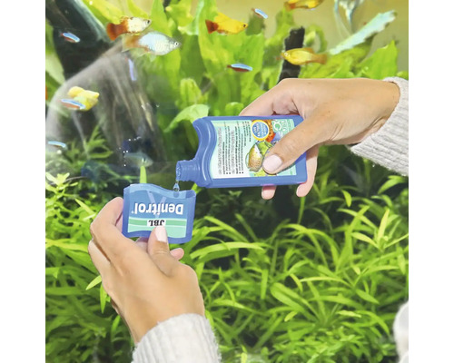 Osoba dávkuje bakteriální startér JBL Denitrol před akváriem