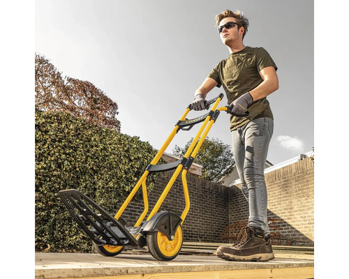 Muž tlačí žluto-černý rudl Stanley na zahradě.