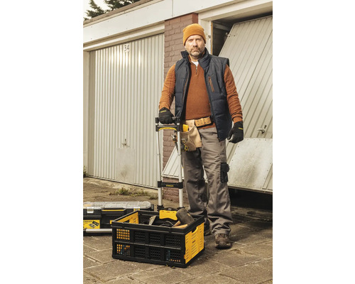 Řemeslník před garážemi s bednou na nářadí a nářadím