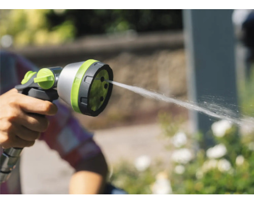 Ruka drží zahradní stříkací pistoli, ze které vytéká voda.