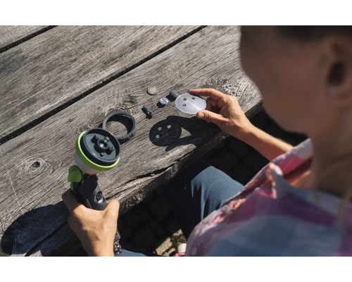 Žena demontuje zahradní postřikovač na dřevěném stole