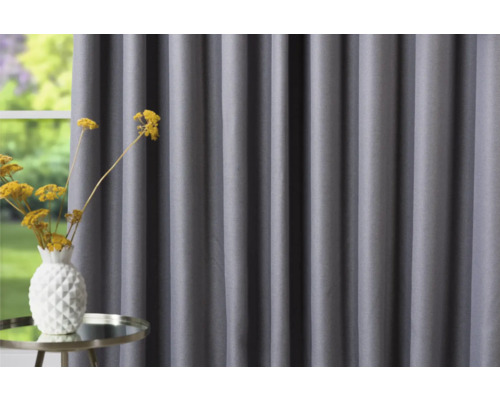 Šedý závěs vedle stolu s vázou květin