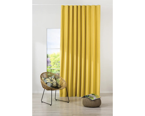 Žlutý závěs vedle okna, ratanové křeslo a stolička
