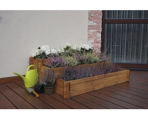Dřevěný truhlík s vřesem a hortenziemi, konev a zahradní lopatka na terase