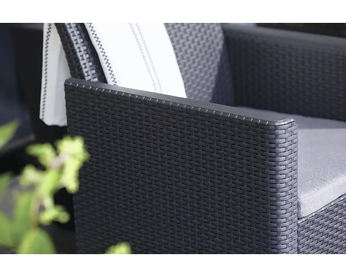 Detailní pohled na černé ratanové křeslo s polštáři