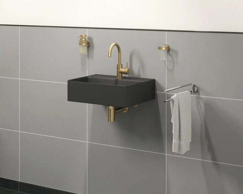 Moderní koupelna s černým umyvadlem, zlatou baterií a držákem na ručníky