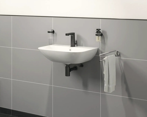 Nástěnné umyvadlo s vodovodní baterií, dávkovačem mýdla, kelímkem na zubní kartáčky a držákem na ručníky v koupelně.