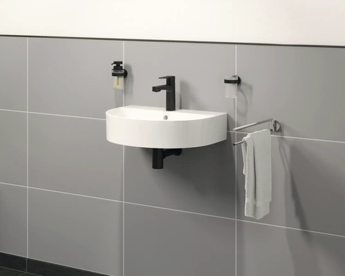 Moderní koupelna s umyvadlem na desku, baterií, dávkovačem mýdla a držákem na ručníky na zdi.